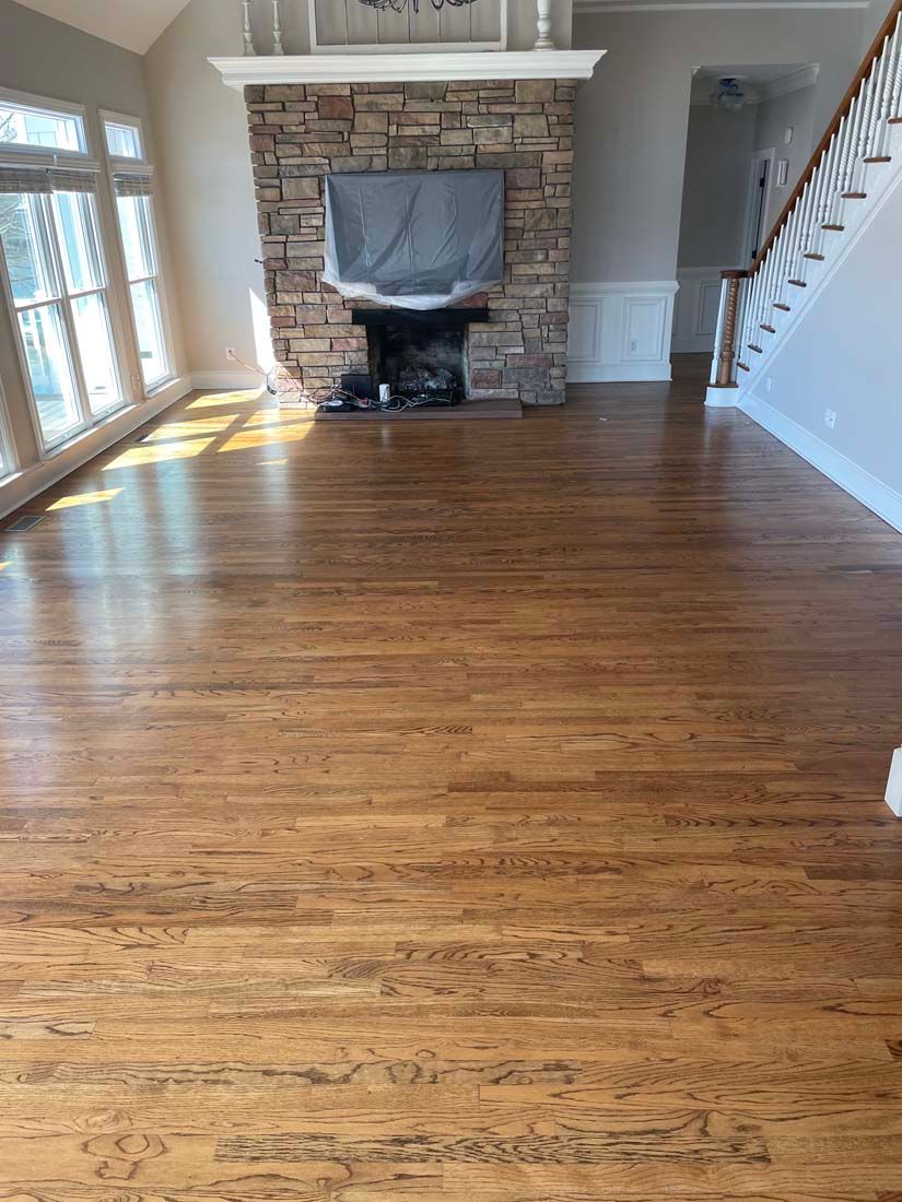 A living room with hardwood floors and a stone fireplace.