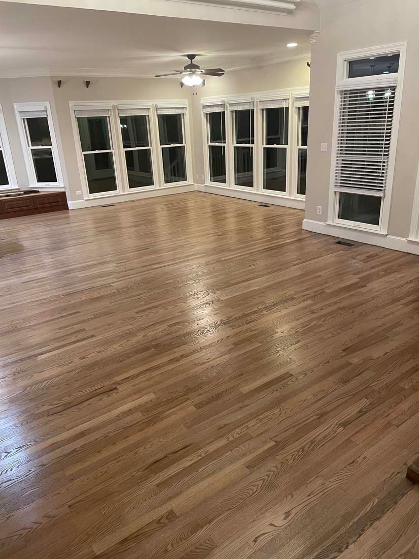 A large empty room with hardwood floors and lots of windows.