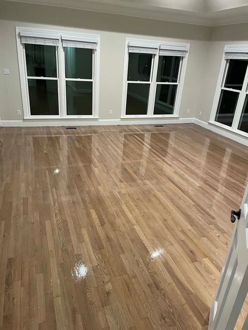 An empty living room with hardwood floors and windows.