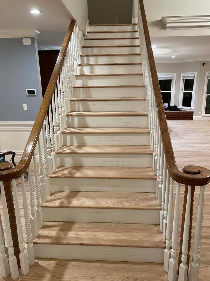A white staircase with wooden steps and a wooden railing in a house.