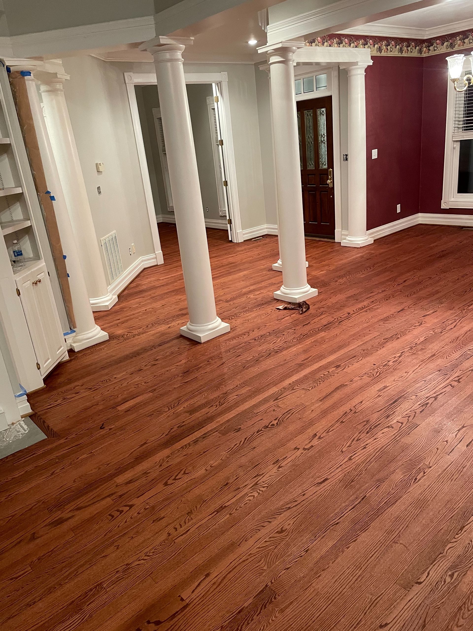 A living room with hardwood floors and white columns.