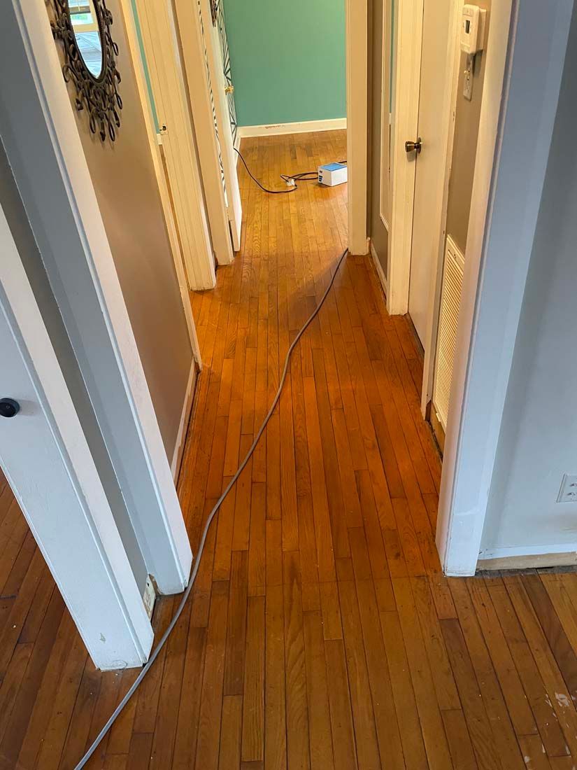 A hallway with hardwood floors and a cord between two doors.