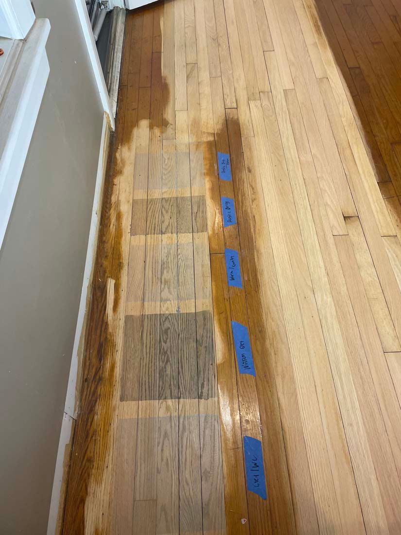 A wooden floor with blue tape on it is being restored.