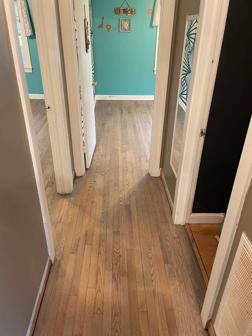 A hallway with hardwood floors and blue walls in a house.