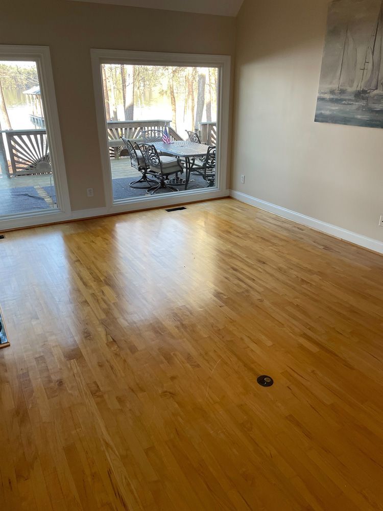 A living room with hardwood floors and a sliding glass door leading to a deck.
