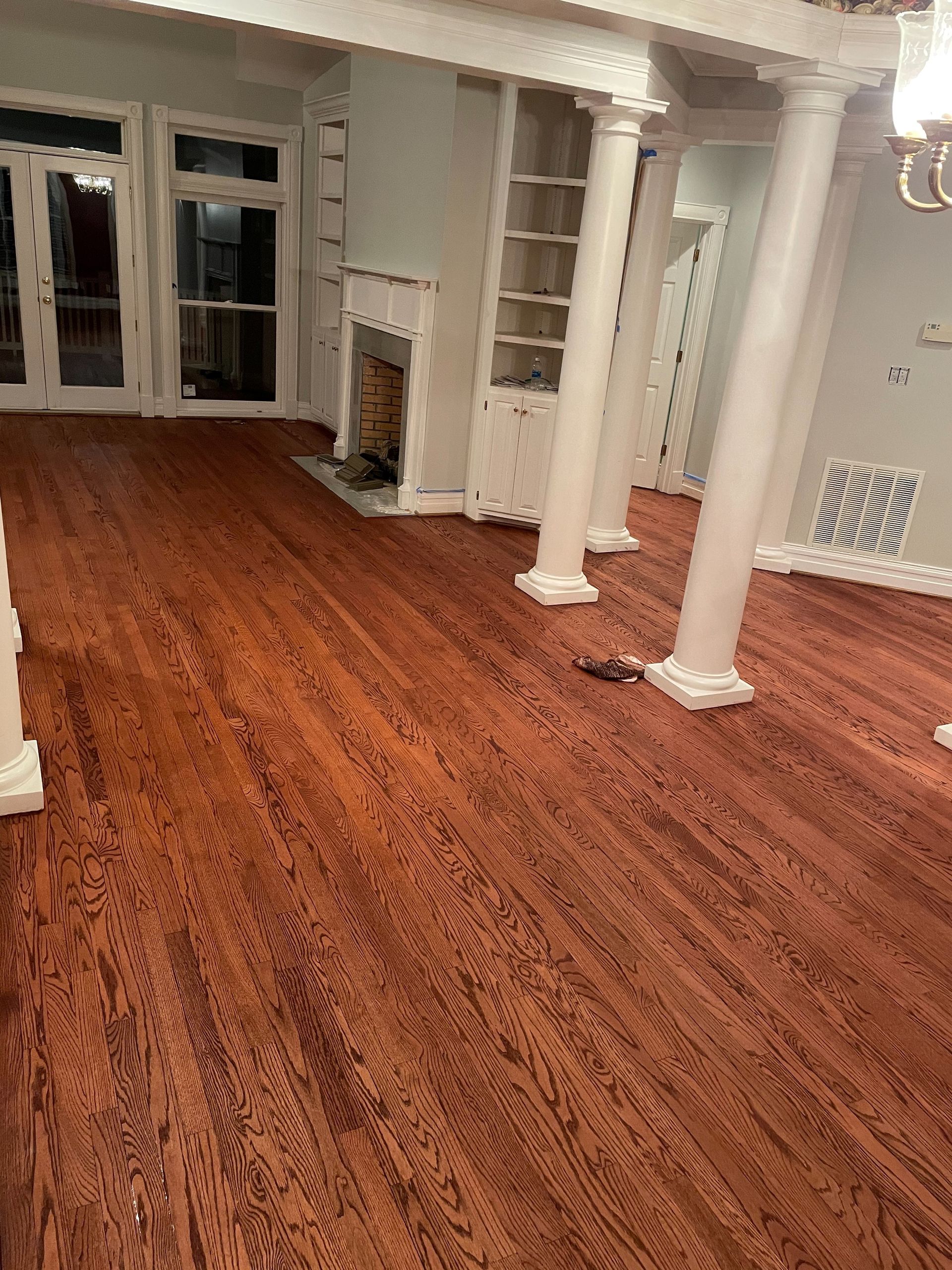 A living room with hardwood floors , columns and a fireplace.