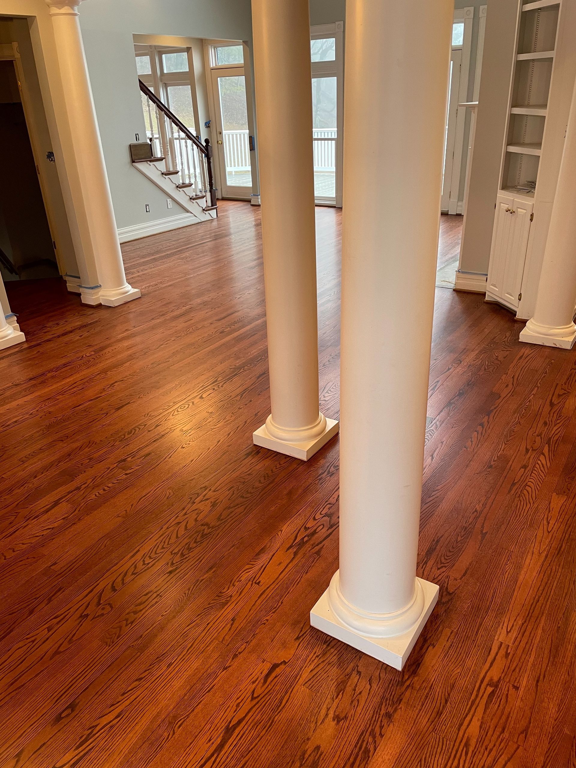 A living room with hardwood floors and white columns.