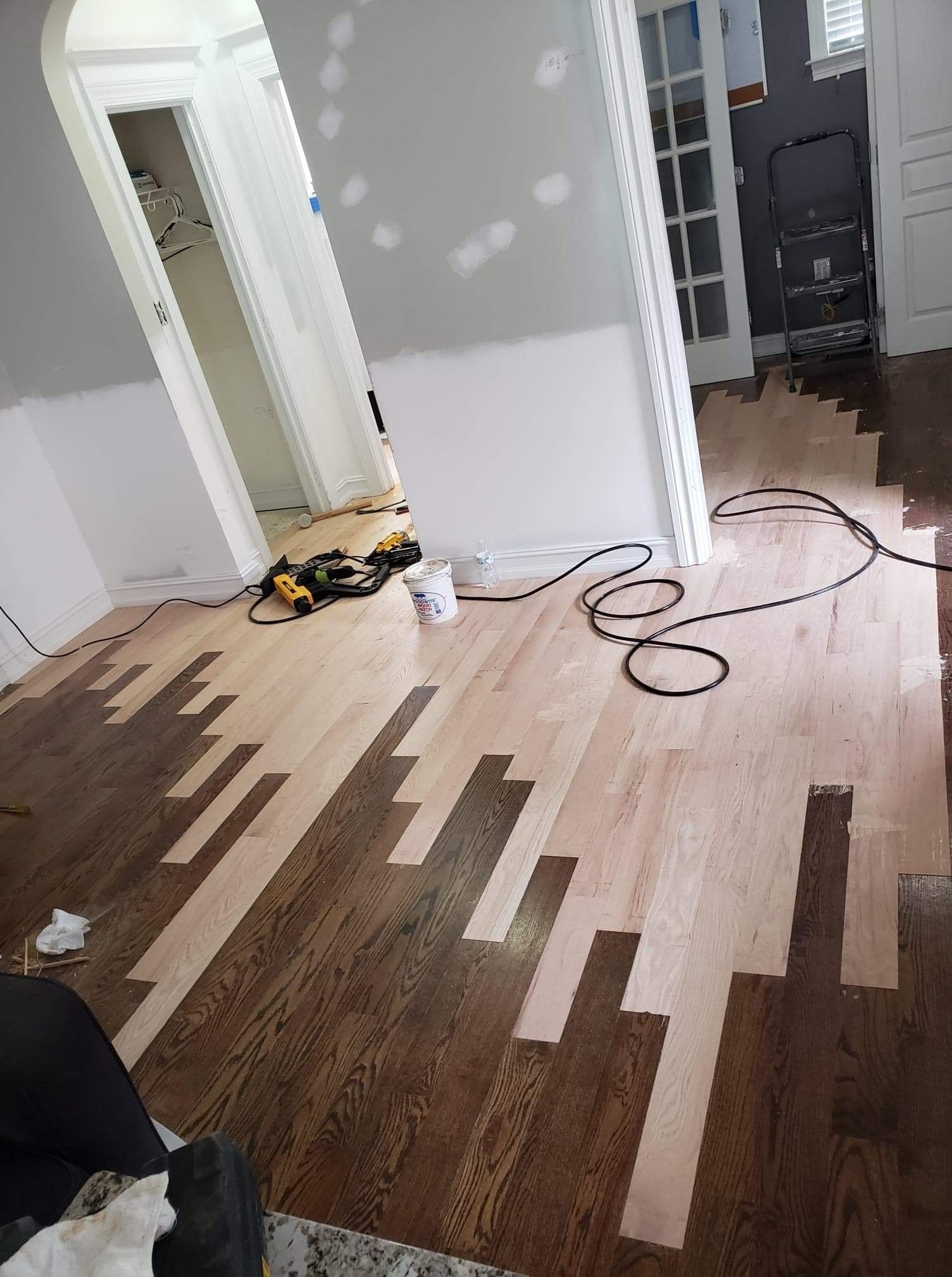 A wooden floor is being painted in a living room.