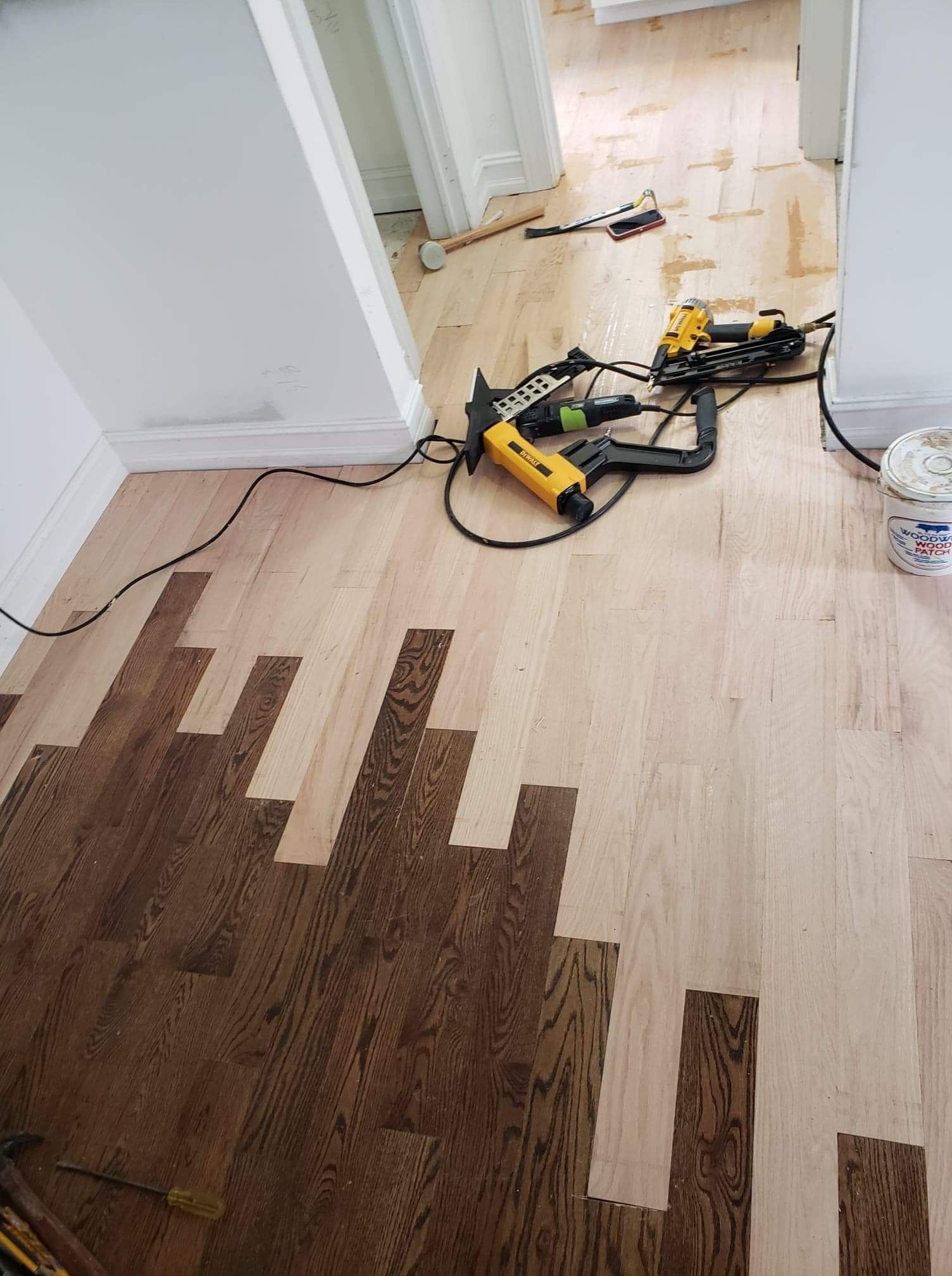 A wooden floor with a drill and stapler on it.