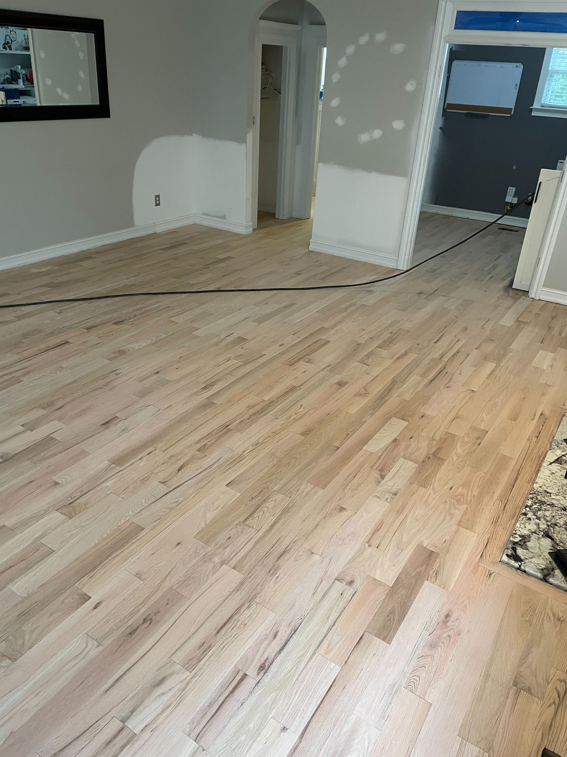 A living room with hardwood floors and a mirror.