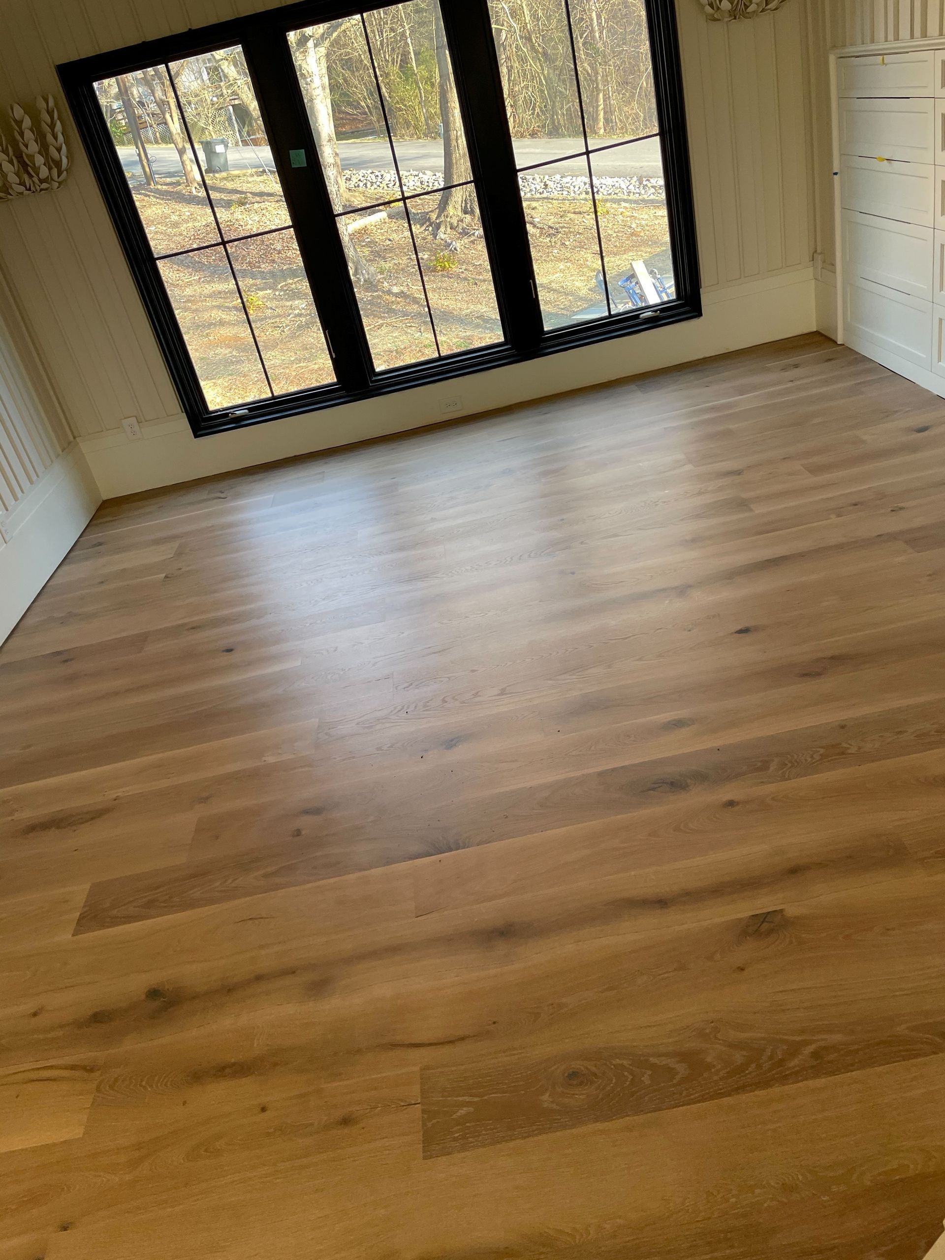 A room with a wooden floor and three windows.