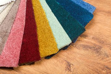 A bunch of different colored carpet samples on a wooden table.