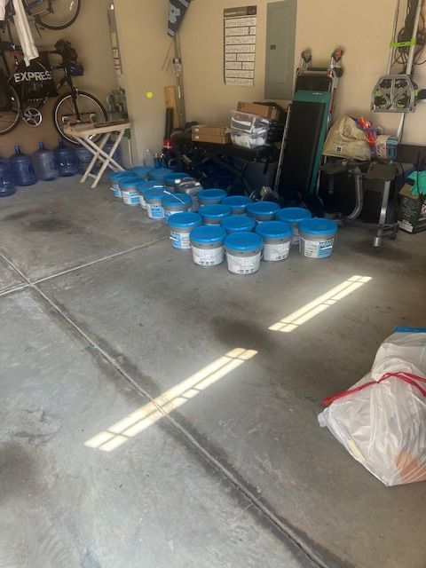 A bunch of blue buckets are sitting on the floor of a garage.