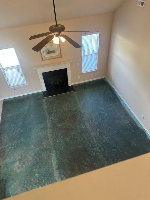 A living room with a fireplace and a ceiling fan.