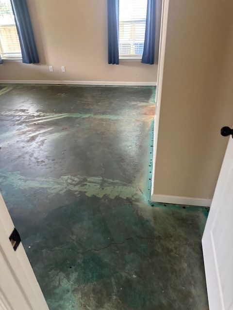 A room with a concrete floor and a door leading to a window.