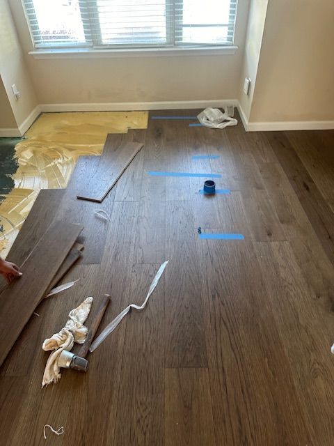 A person is laying wooden flooring in a room.