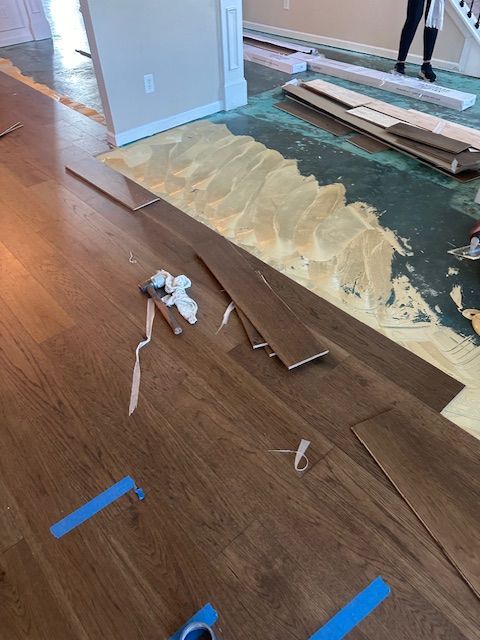 A wooden floor is being installed in a living room.