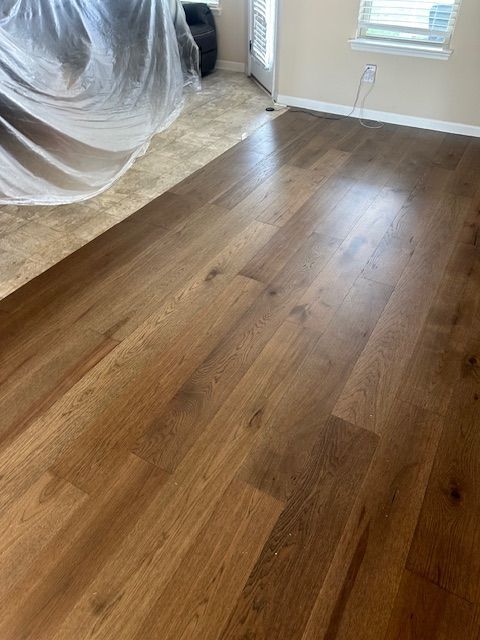 A living room with a wooden floor and a window.