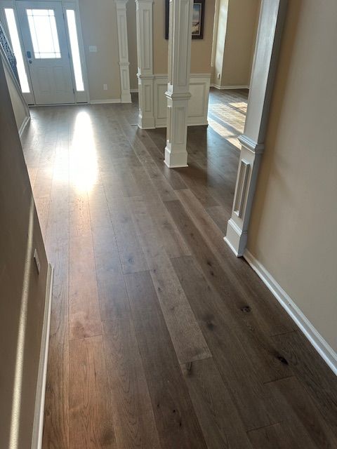 A hallway with hardwood floors and white columns in a house.