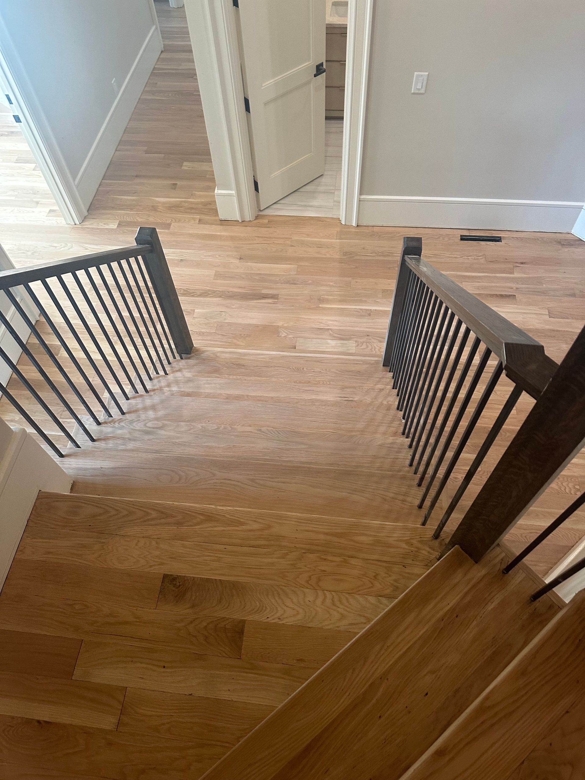 A wooden staircase with a metal railing leading up to the second floor of a house.