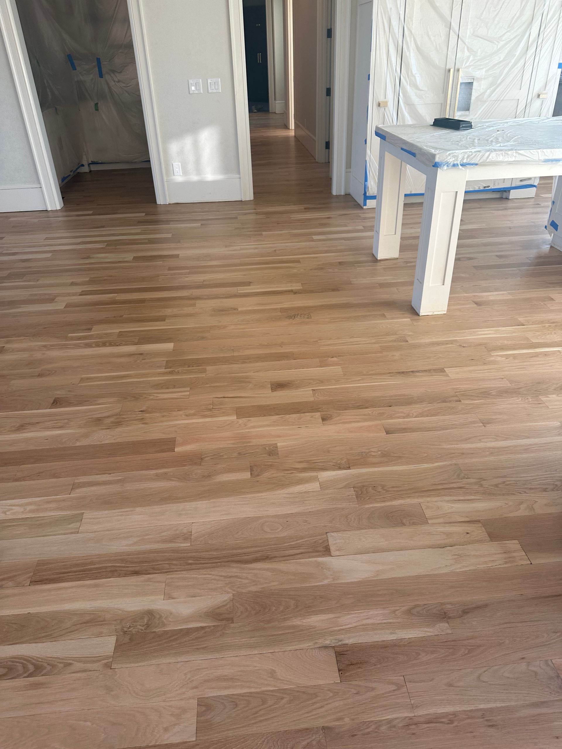 A wooden floor with a table in the middle of the room.