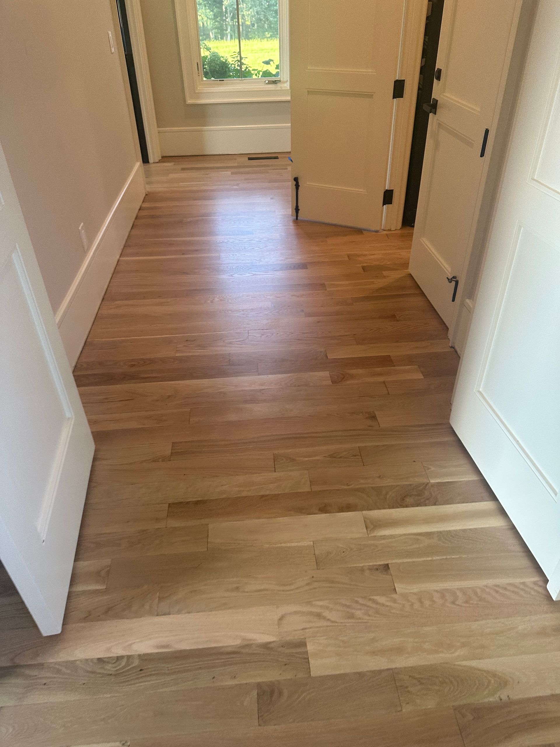 A hallway with hardwood floors and white doors in a house.