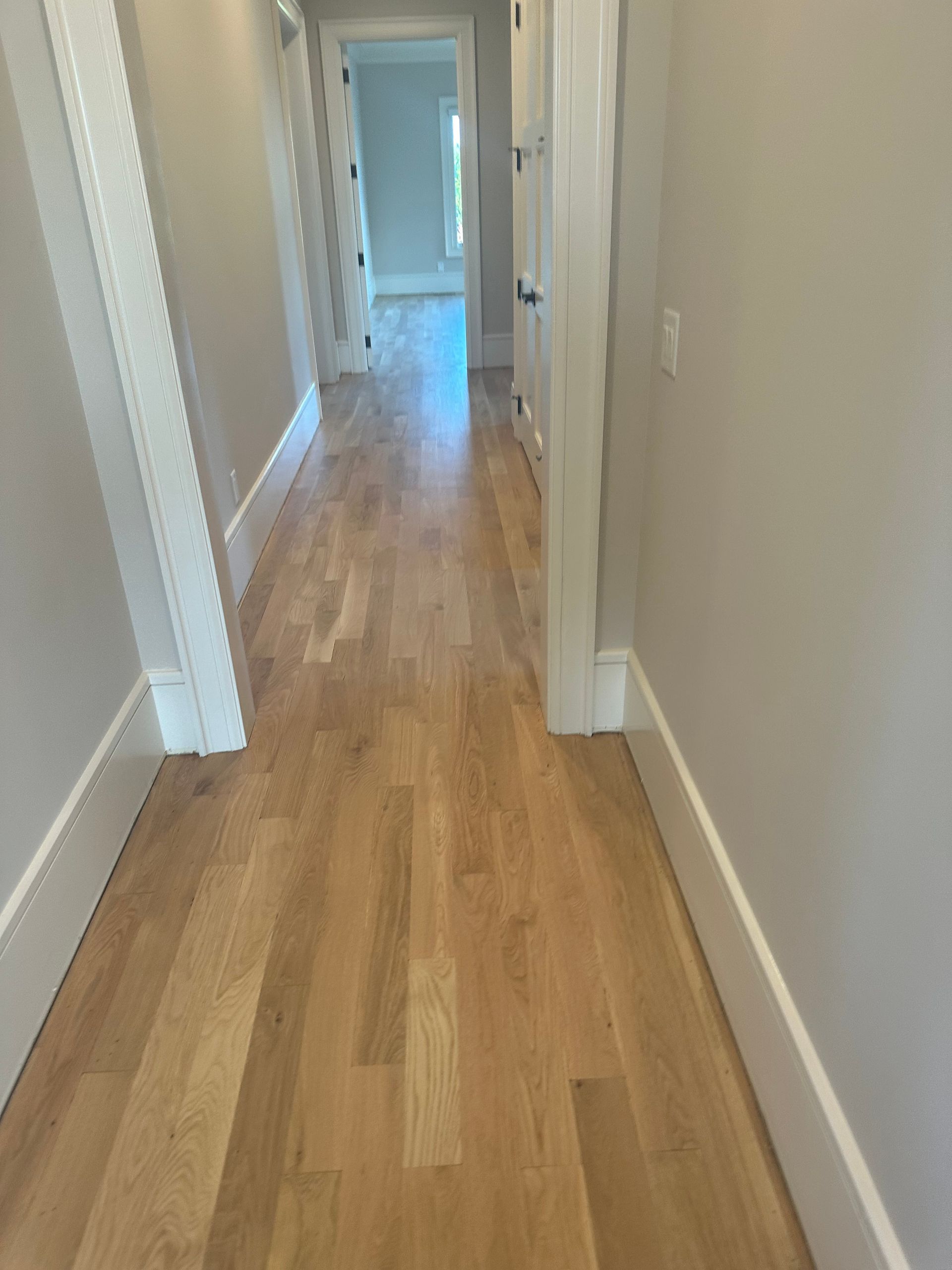 A hallway with hardwood floors and white trim in a house.