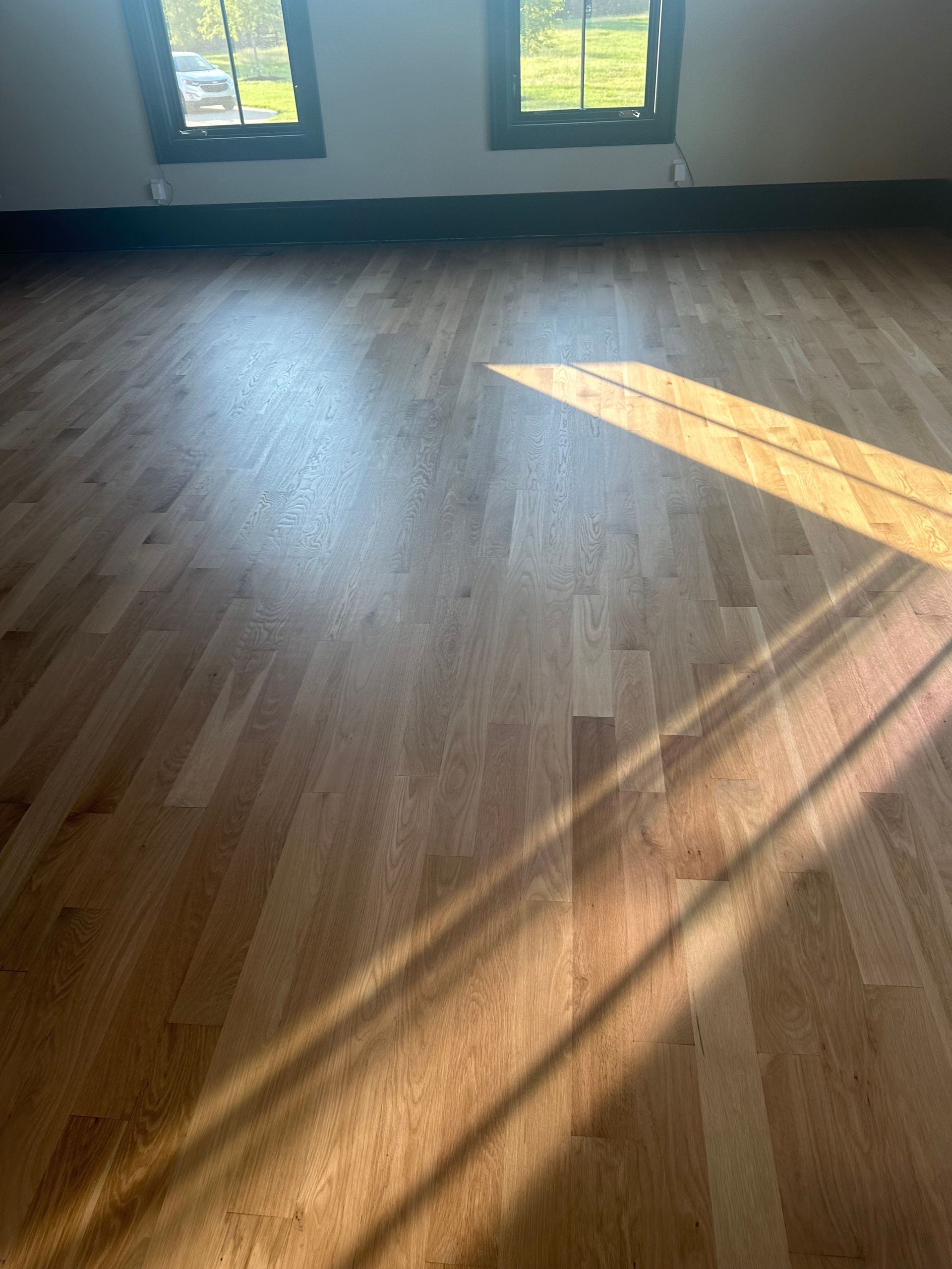 A room with a wooden floor and two windows.