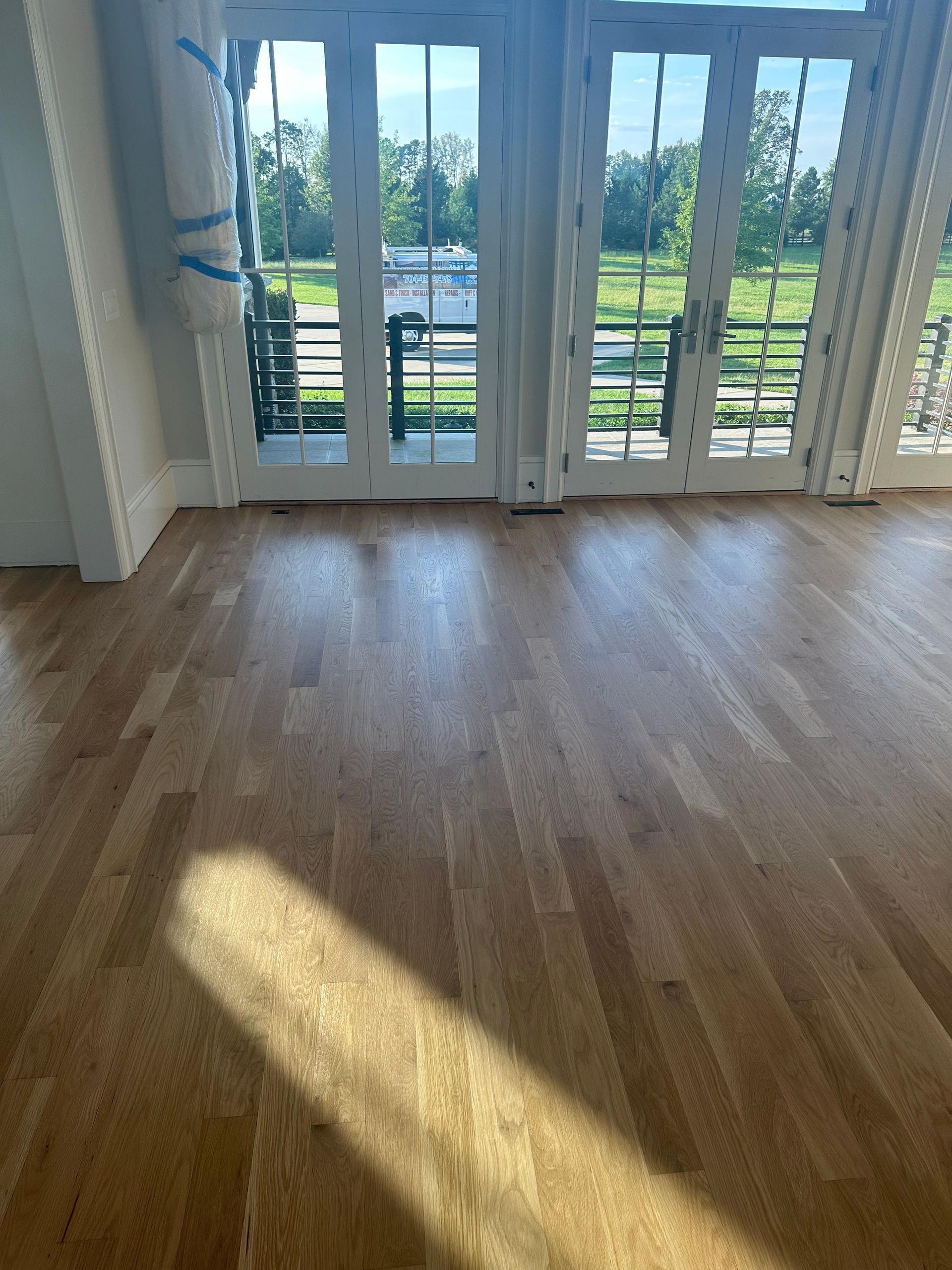 An empty room with hardwood floors and french doors.
