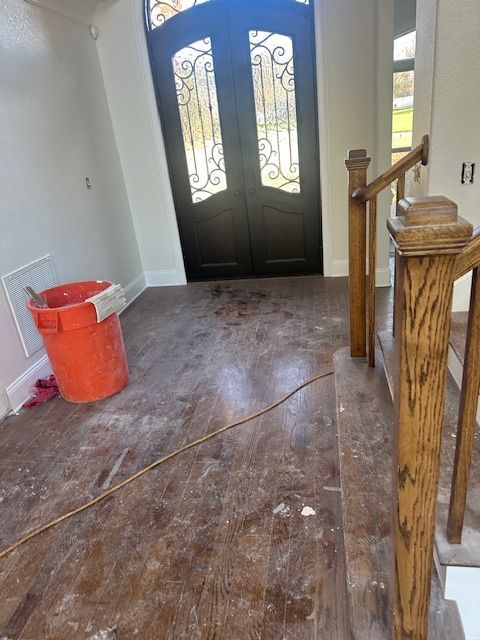 An empty hallway with stairs and a bucket on the floor