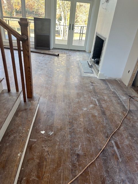 A dirty living room with a fireplace and stairs.