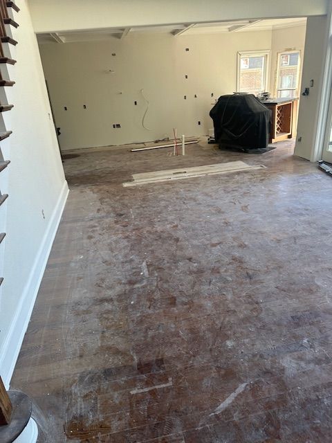 A large empty room with a wooden floor and white walls.