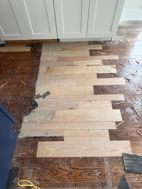 A wooden floor is being installed in a kitchen.