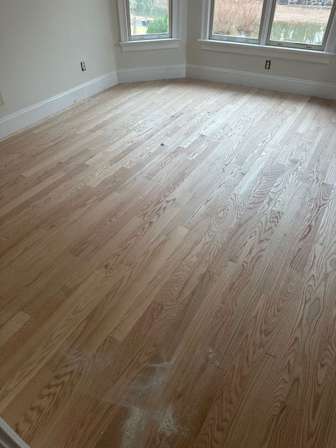 A living room with hardwood floors and two windows.