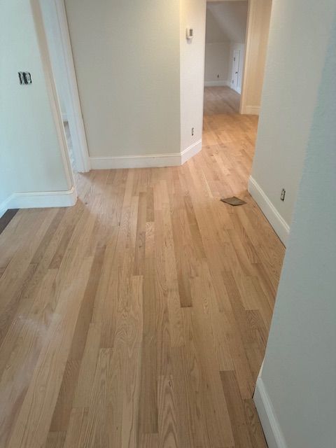 A hallway with hardwood floors and white walls in a house.