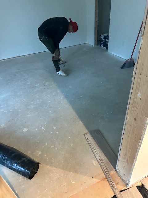 A man in a red hat is bending over on the floor.