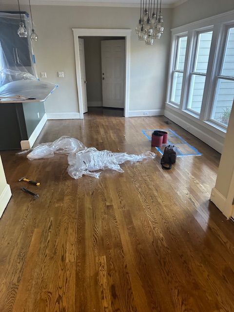 An empty room with hardwood floors and a lot of windows.