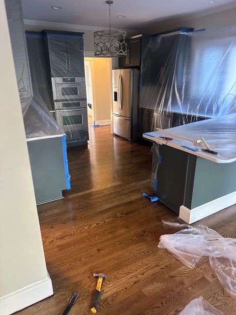 A kitchen is being painted and covered in plastic.