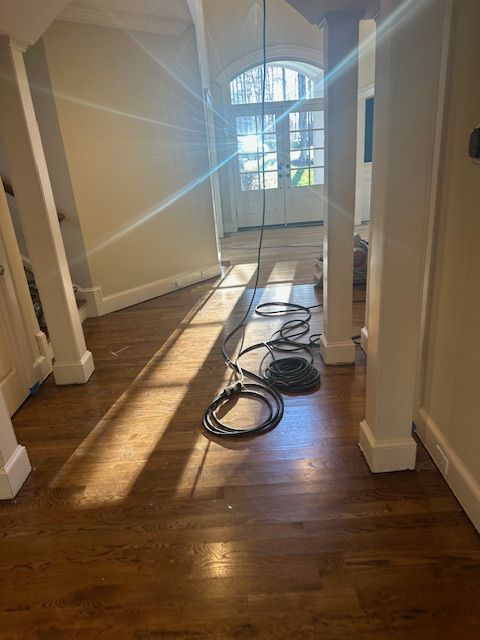 A hallway with hardwood floors and white pillars in a house.