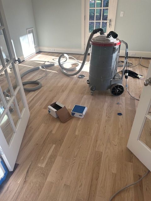 A vacuum cleaner is sitting on a wooden floor in a room.