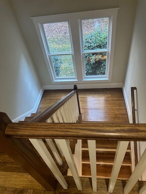 A wooden staircase with a white railing and a window