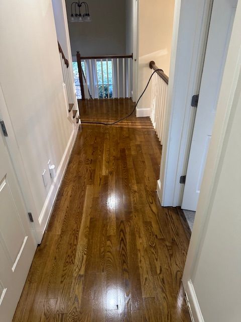 A hallway with hardwood floors and stairs in a house.