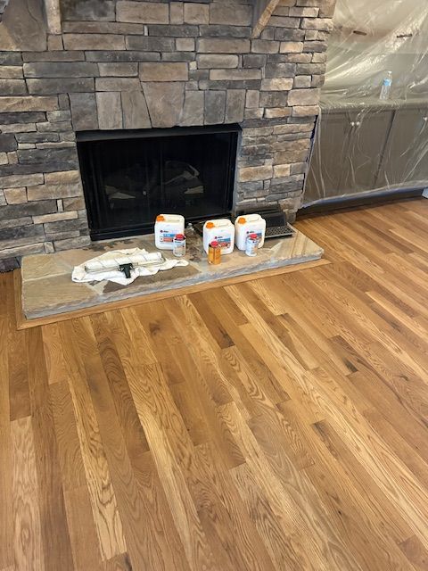 A living room with hardwood floors and a stone fireplace.