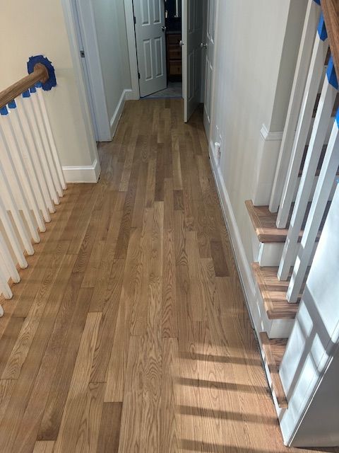 A hallway with hardwood floors and stairs in a house.