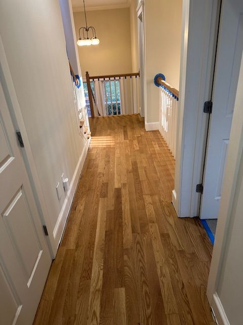 A hallway with hardwood floors leading to a staircase in a house.