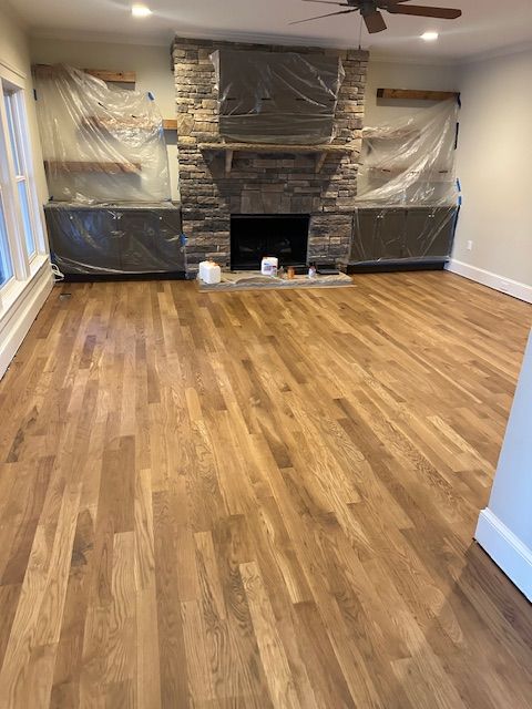 A living room with hardwood floors and a stone fireplace.