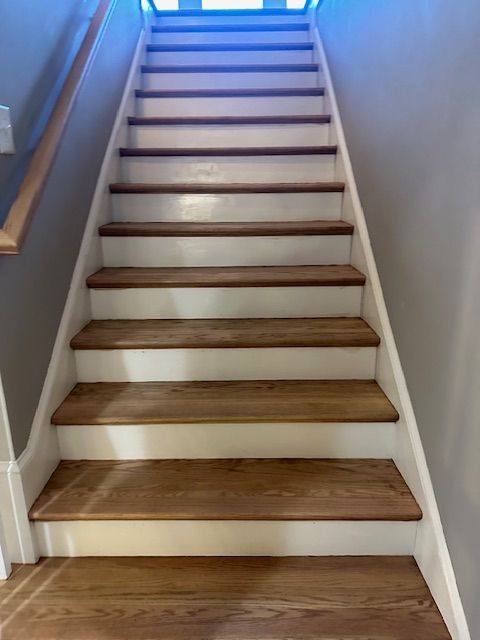 A staircase with wooden steps and white railing in a house.