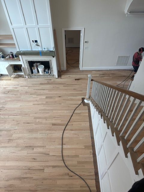 A man is working on a wooden floor in a living room.