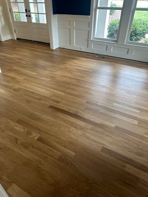 A living room with hardwood floors and a lot of windows.