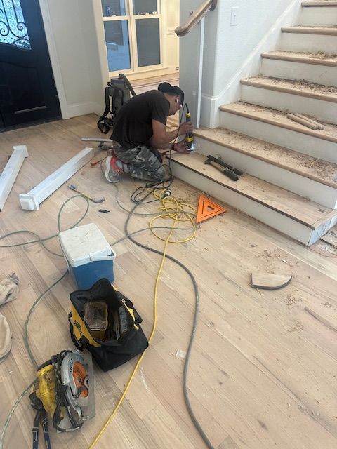A man is kneeling on the floor working on a set of stairs.